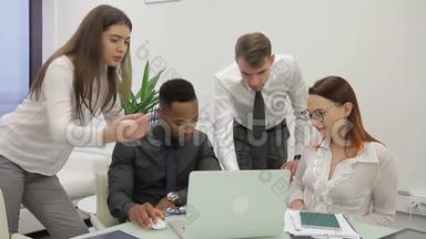 工作组正在办公桌上用笔记本电脑在现代办公室交谈。